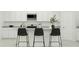 Modern kitchen island with three black barstools at 12517 W Trumbull Rd, Avondale, AZ 85323