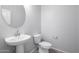 Clean bathroom with pedestal sink, toilet, and oval mirror at 18972 W Woodlands Ave, Buckeye, AZ 85326