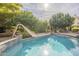 Relaxing pool area with a slide and patio furniture, surrounded by lush greenery at 2124 E Virginia St, Mesa, AZ 85213