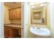 Small half bathroom with pedestal sink and wood cabinets at 2124 E Virginia St, Mesa, AZ 85213