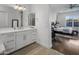 Bathroom with white cabinets, a large mirror, and view into bedroom at 8400 E Columbus Ave, Scottsdale, AZ 85251