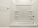 This is an up-close view of the white tub and shower combination with built-in shelving at 9108 N 174Th Ln, Waddell, AZ 85355