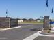 Welcoming community entrance with a paved road, decorative stone pillars, and clear blue skies at 9108 N 174Th Ln, Waddell, AZ 85355