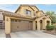 Two-story house with tan exterior, brown garage door, and landscaping at 14595 W Acapulco Ln, Surprise, AZ 85379