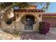 Front entry with arched doorway, wrought iron gate, and purple flowers at 10473 N 87Th Pl, Scottsdale, AZ 85258