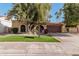 Tan stucco house with brown garage door, lush lawn, and mature trees at 10473 N 87Th Pl, Scottsdale, AZ 85258