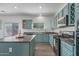 Modern kitchen with teal cabinets, granite counters, and stainless steel appliances at 11860 W Grant St, Avondale, AZ 85323