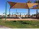 Community playground with swings shaded by a large awning at 3830 E Lakewood Pkwy # 1166, Phoenix, AZ 85048