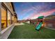 Beautiful backyard with lush artificial grass, play structure, and outdoor dining area at sunset at 32722 N 132Nd Ln, Peoria, AZ 85383