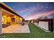 Backyard featuring a covered patio, dining set, a fire pit and desert landscaping at dusk at 32722 N 132Nd Ln, Peoria, AZ 85383