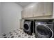 Well organized laundry room with upper and lower cabinets and modern front load machines at 32722 N 132Nd Ln, Peoria, AZ 85383