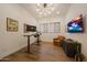 Modern office with adjustable desk, bright lighting, hardwood floors and wall-mounted television at 32722 N 132Nd Ln, Peoria, AZ 85383