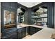 Elegant wet bar featuring dark cabinetry, a wine fridge, mirrored backsplash, and open shelving for glassware and bottles at 6800 E Caballo Dr, Paradise Valley, AZ 85253