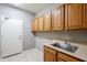 Laundry room with wood cabinets, utility sink, and exterior access at 1060 W Silver Creek Rd, Gilbert, AZ 85233