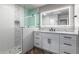 Modern bathroom with a large mirror, walk-in shower, and white cabinets at 25037 S Ribbonwood Dr, Sun Lakes, AZ 85248