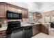 Kitchen with dark brown cabinets and black appliances at 9543 E Palomino Pl, Sun Lakes, AZ 85248