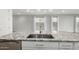 A close-up of a kitchen island with granite counters, stainless steel sink and faucet, and an open view into the living room at 9658 E Tahoe Cir, Mesa, AZ 85212