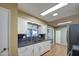 White kitchen cabinets, granite countertops, and a double sink at 9909 W Newport Dr, Sun City, AZ 85351