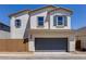 Two-story home featuring stucco siding, blue shutters, and a two-car garage under a bright blue sky at 14644 W Sand Hills Rd, Surprise, AZ 85387