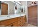 Double vanity bathroom with light wood cabinets and a view into a bedroom at 18009 W Denton Ave, Litchfield Park, AZ 85340