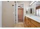 Bathroom with double sinks, wood cabinets, and a view of a bedroom at 18009 W Denton Ave, Litchfield Park, AZ 85340