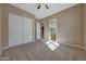 Bedroom with carpet, ceiling fan, and view to bathroom and closet at 18009 W Denton Ave, Litchfield Park, AZ 85340