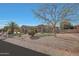 Beautiful single-story home with desert landscaping, mature trees, and a well-manicured lawn at 18009 W Denton Ave, Litchfield Park, AZ 85340