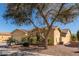 House exterior showcasing a tan stucco finish and mature tree in front at 42899 W Whimsical Dr, Maricopa, AZ 85138