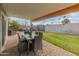 Covered patio with pavers, outdoor dining set, and grassy backyard at 7443 E Taylor St, Scottsdale, AZ 85257