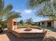 Brick fire pit and built-in BBQ in backyard with grassy area and mature trees at 7550 E Ironwood Ct, Scottsdale, AZ 85258