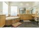 Large bathroom with corner bathtub, double vanity, and wood cabinets at 9580 E Southwind Ln, Scottsdale, AZ 85262