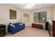 Bedroom with a blue sofa, dresser, and window at 26602 S Nicklaus Dr, Sun Lakes, AZ 85248