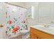 Clean bathroom with floral shower curtain, wood vanity, and tile floor at 40901 N Courage Trl, Anthem, AZ 85086