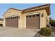 Tan two-story house with a three-car garage and landscaped yard at 20359 N 262Nd Dr, Buckeye, AZ 85396