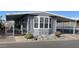 Gray manufactured home with covered porch, landscaping, and a paved driveway at 205 S Higley Rd # 299, Mesa, AZ 85206