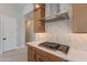 Modern kitchen with gas cooktop, stainless steel range hood, and custom cabinetry at 21418 W Meadowbrook Ave, Buckeye, AZ 85396