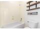 Clean bathroom with a tub, toilet and wooden shelves at 2410 W Aloe Vera Dr, Phoenix, AZ 85085