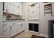 White laundry room cabinets, utility sink, and vintage-style door at 27028 W Oraibi Dr, Buckeye, AZ 85396