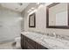 Bathroom featuring dual sinks with granite countertops, dark wood cabinets, and a tiled walk-in shower at 3106 E Hiddenview Dr, Phoenix, AZ 85048