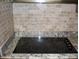 Close-up of a smooth cooktop with granite countertops and decorative tile backsplash at 10731 W Mission Ln, Sun City, AZ 85351