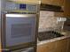 Kitchen featuring stainless steel double oven, smooth cooktop, granite countertops, and decorative backsplash at 10731 W Mission Ln, Sun City, AZ 85351