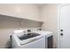 Bright laundry room featuring a modern washer and dryer set and overhead shelving at 11346 E Renata Ave, Mesa, AZ 85212