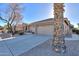 Home's exterior featuring a large palm tree and a two-car garage at 143 S Los Cielos Ln, Casa Grande, AZ 85194