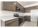 Modern kitchen with dark wood cabinets, quartz countertops, and stainless steel appliances at 1447 S 239Th Dr, Buckeye, AZ 85326