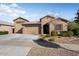 Tan two-story house with a three car garage and landscaped front yard at 24211 N 168Th Ln, Surprise, AZ 85387