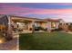 Backyard patio at sunset with artificial turf and covered patio at 27453 W Wahalla Ln, Buckeye, AZ 85396