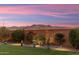 Backyard with artificial turf, mountain views, and sunset at 27453 W Wahalla Ln, Buckeye, AZ 85396