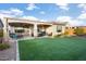 Spacious backyard with covered patio, artificial turf, and mature landscaping at 27453 W Wahalla Ln, Buckeye, AZ 85396