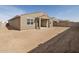 View of the back of the house with empty backyard and small patio at 37073 W La Paz St, Maricopa, AZ 85138