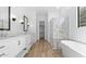 Bathroom showcasing a double vanity, glass-enclosed shower, freestanding tub, and open doorway to closet at 42104 N Golden Trl, San Tan Valley, AZ 85140